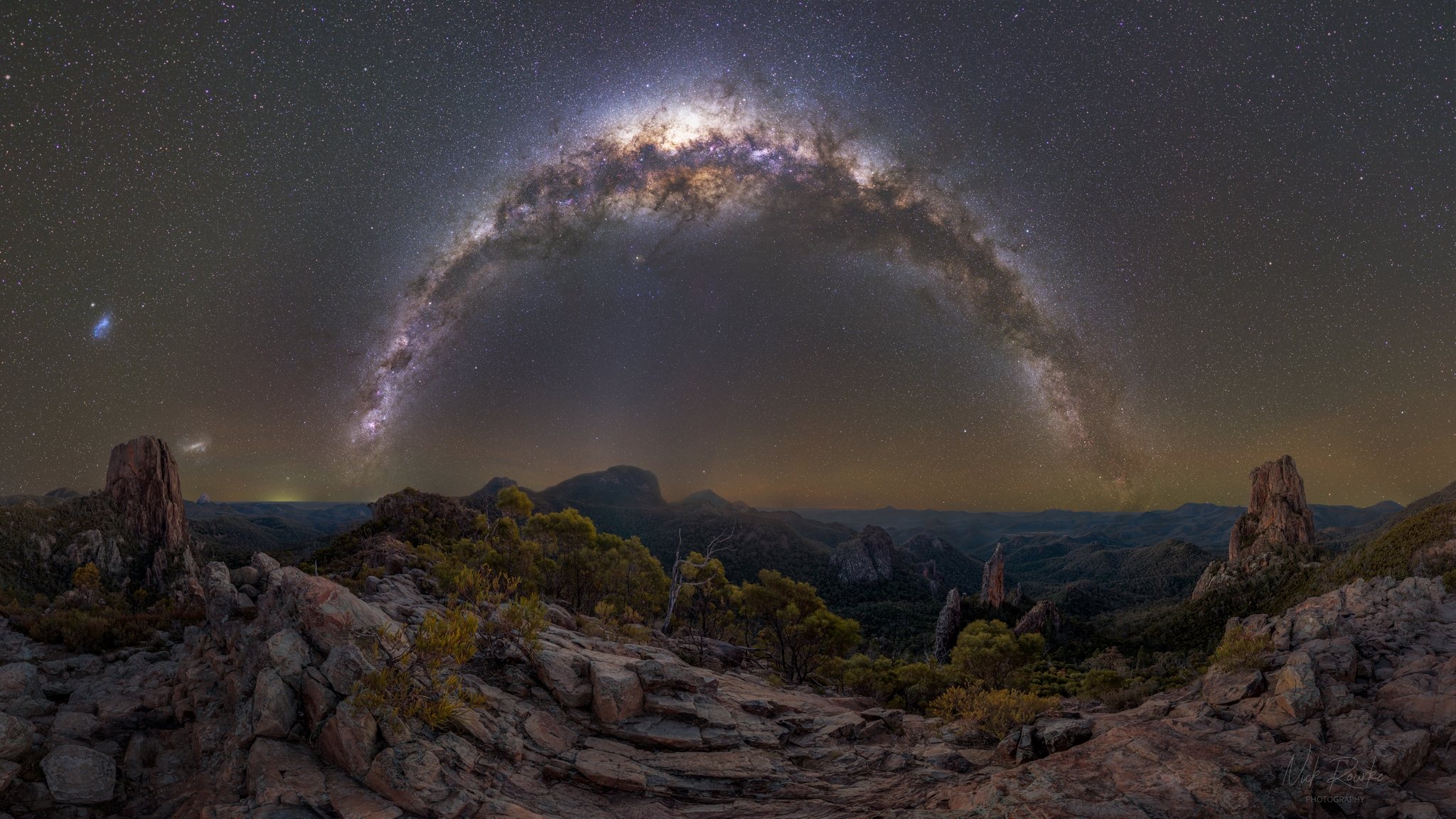 The Milky Way arches over the Warrumbungle range at night